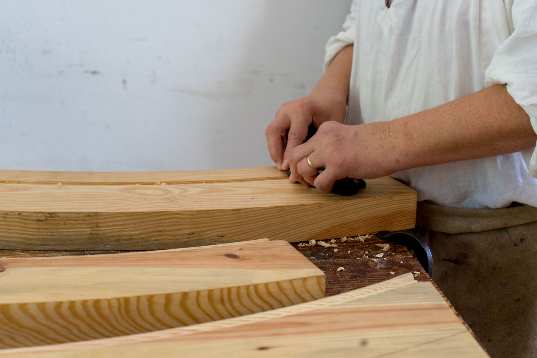 Hands shaping a curved hardwood fender piece by hand