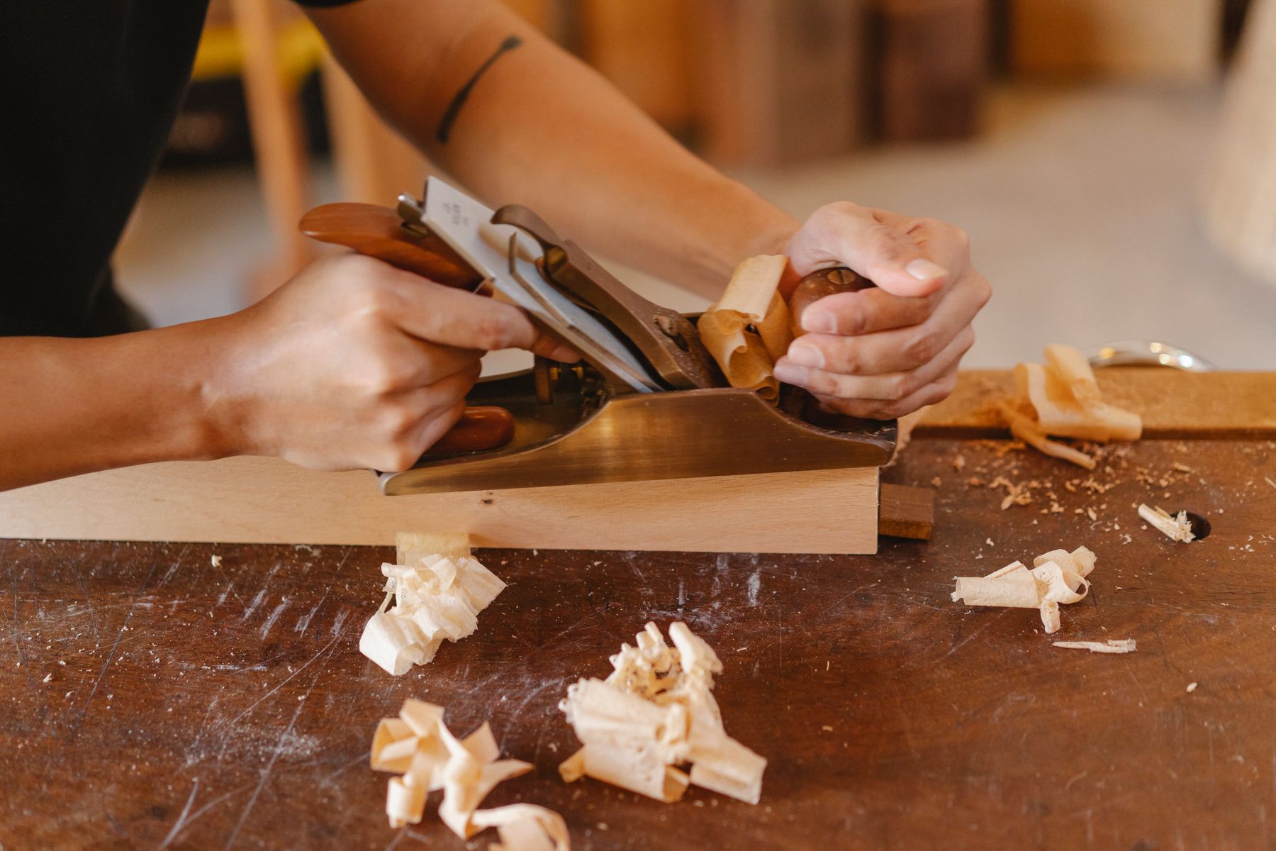 Close-up of a hand plane shaving curls off a hardwood board