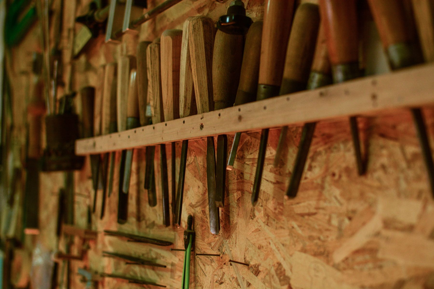 Hand tools and turned wooden spindles on a workshop wall